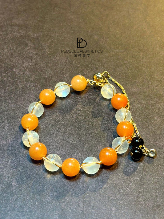 Beaded bracelet with orange and clear stones, gold-tone chain and charm