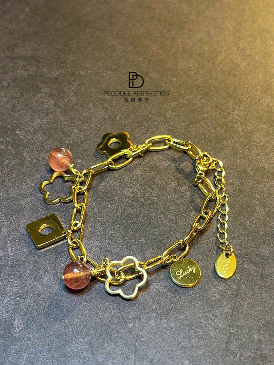 Gold chain bracelet with berry bead charms and small luck symbols, with clasp detail