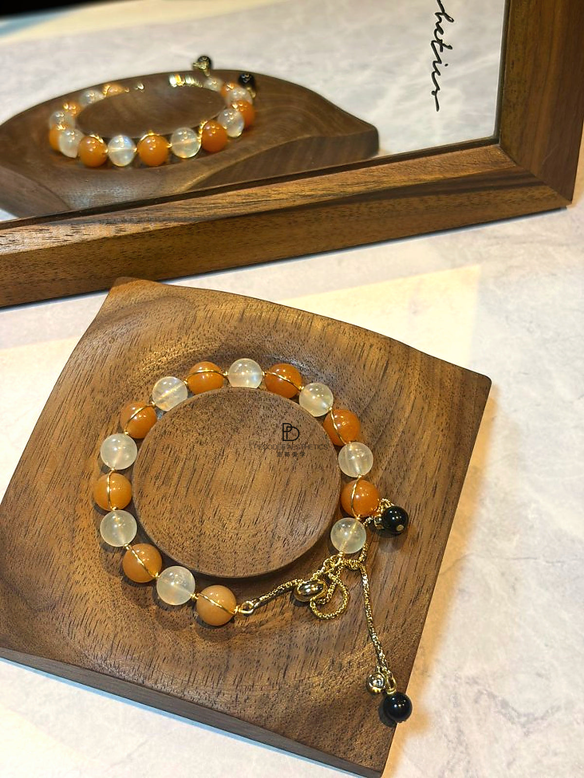 Beaded bracelet with orange, clear, and black beads, gold-tone links and tassel charm