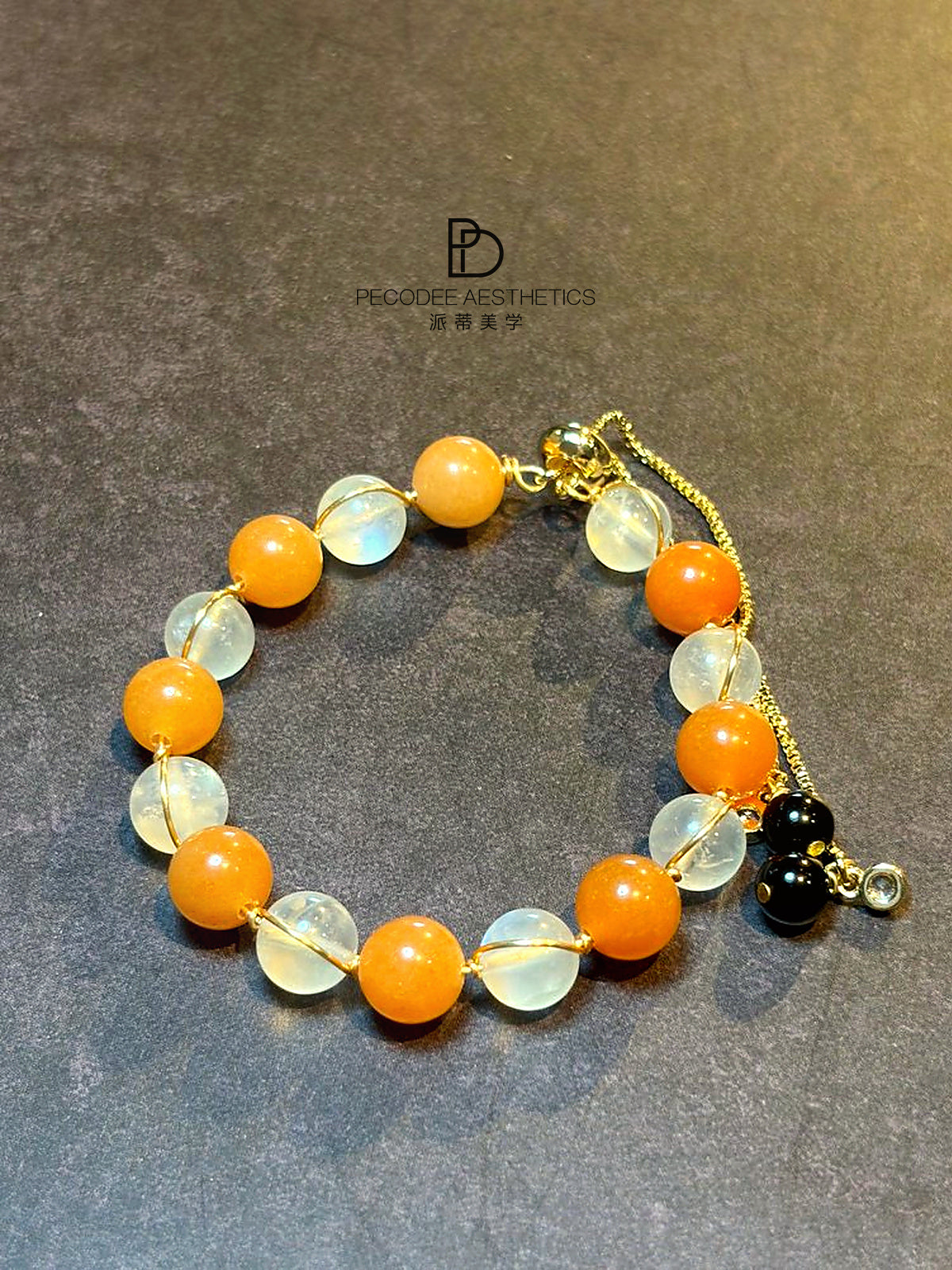 Beaded bracelet with orange and clear stones, gold-tone chain and charm