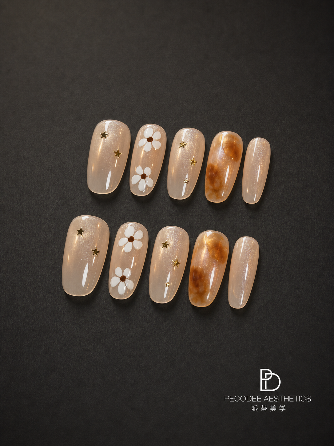 Amber star bloom press-on nails set, nude and amber tips with stars and floral accents.
