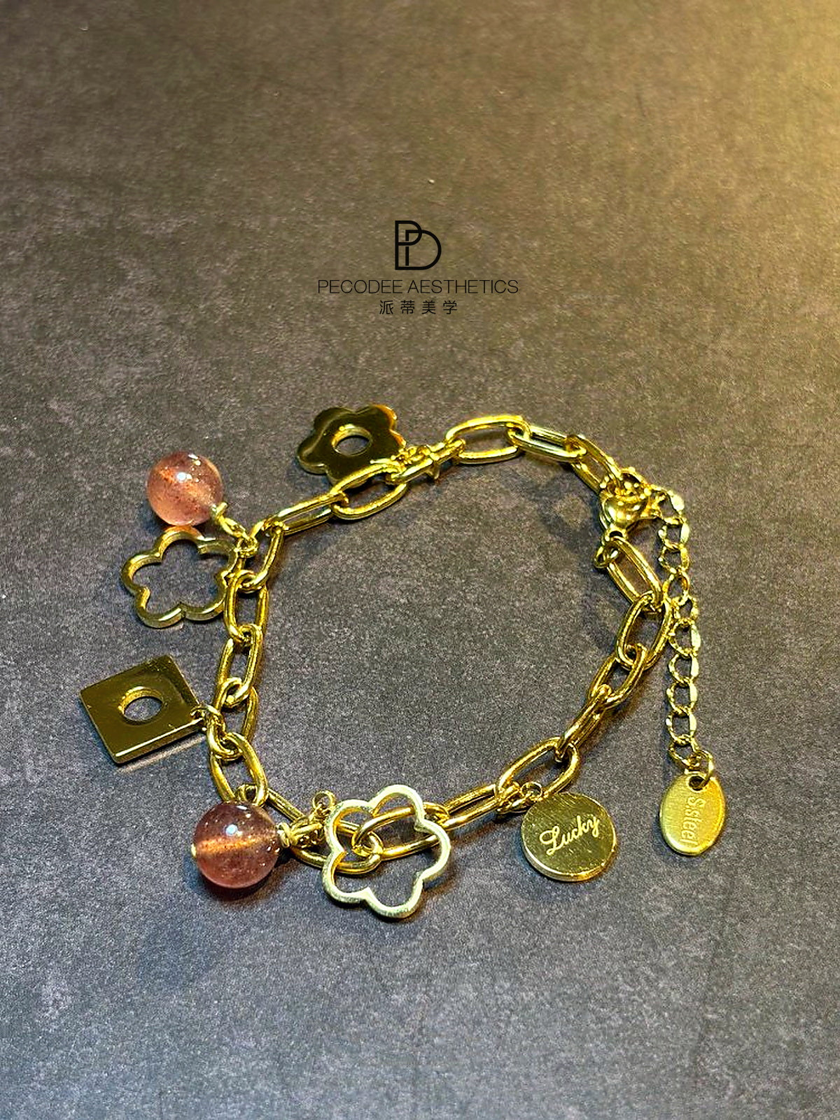 Gold chain bracelet with berry bead charms and small luck symbols, with clasp detail
