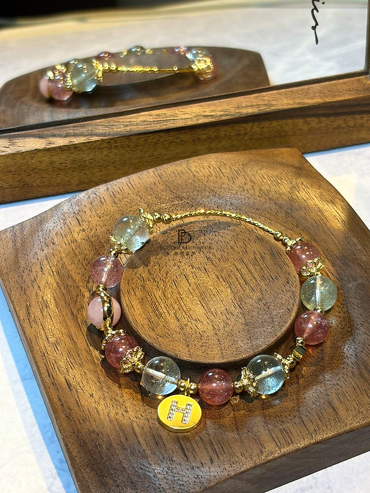 Gold-tone beaded bracelet with pastel glass beads and a yellow enamel letter H charm