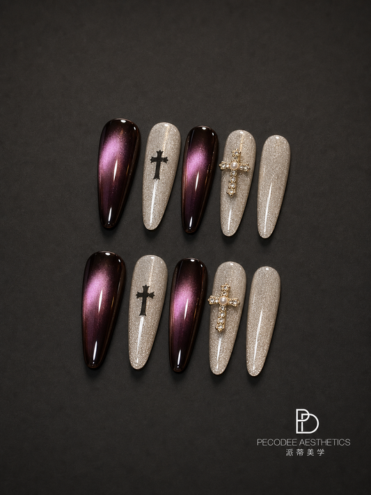 Burgundy press-on nails with glitter tips, cross charms, and rhinestone details