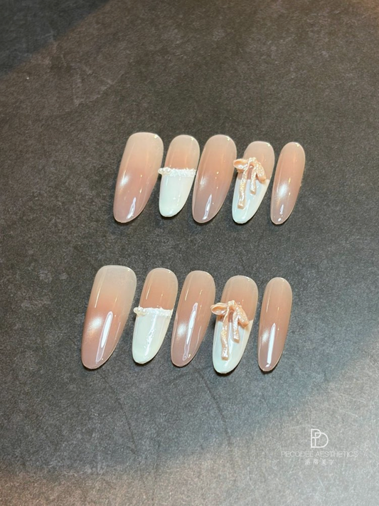 Cream bow nail set with pale nude and white tips, bow accents on two nails