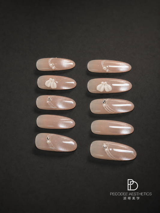 Pearl-carved press-on nail set with creamy nude oval tips and floral charms