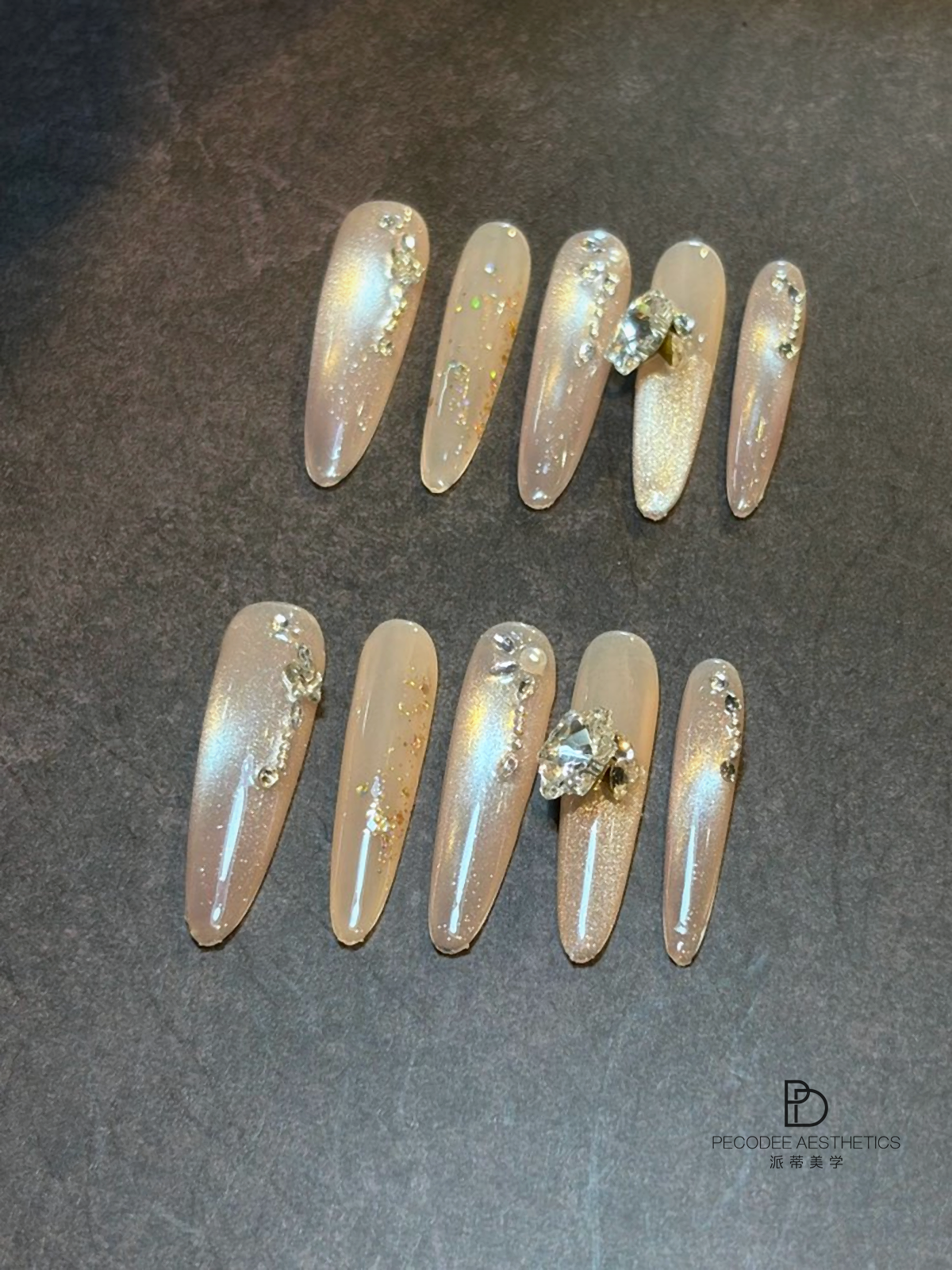 Iridescent press-on nails with glitter, chrome finish, and rhinestone accents