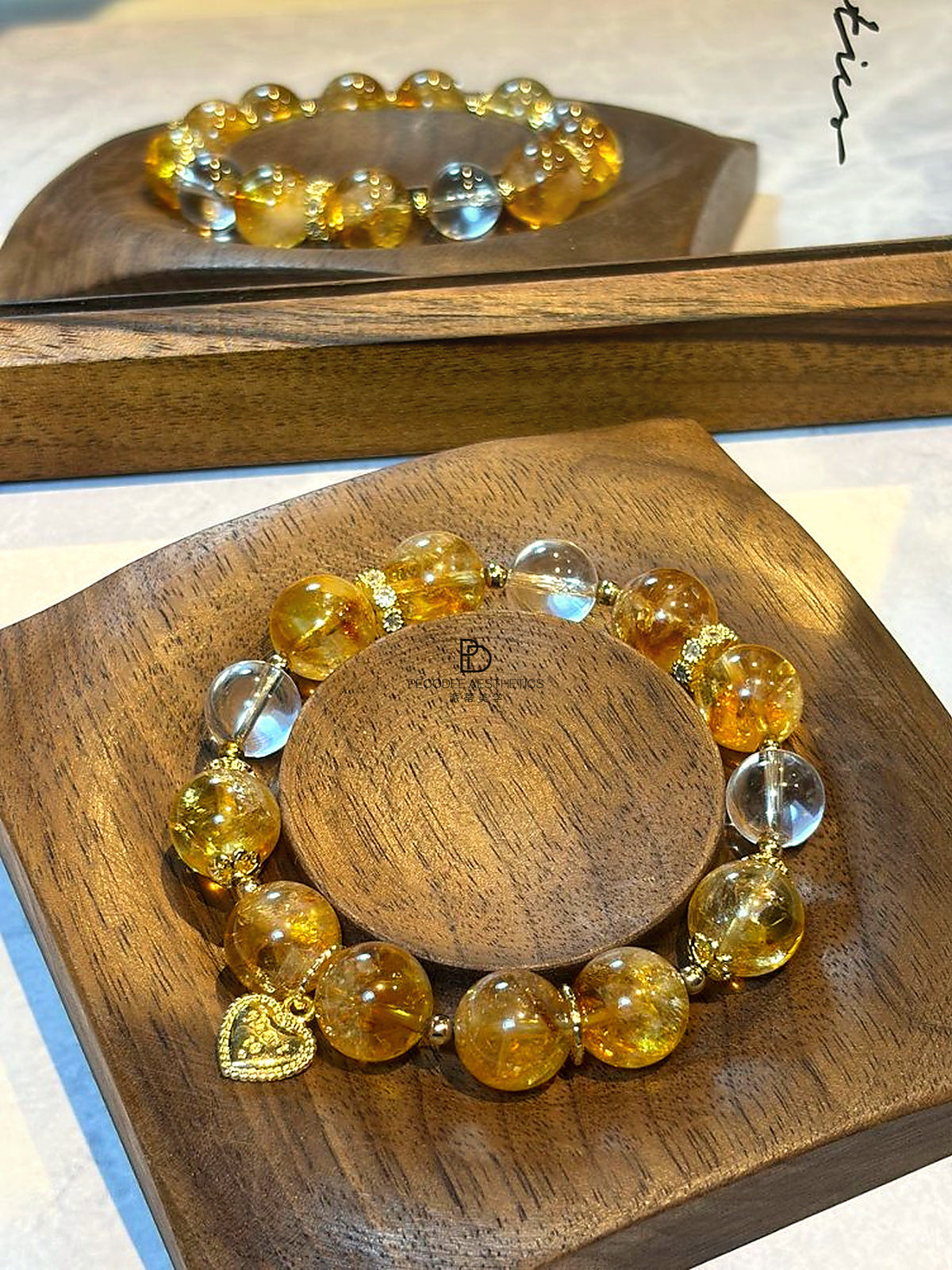 Beaded bracelet with amber-gold beads, clear light-blue beads, and gold heart charm