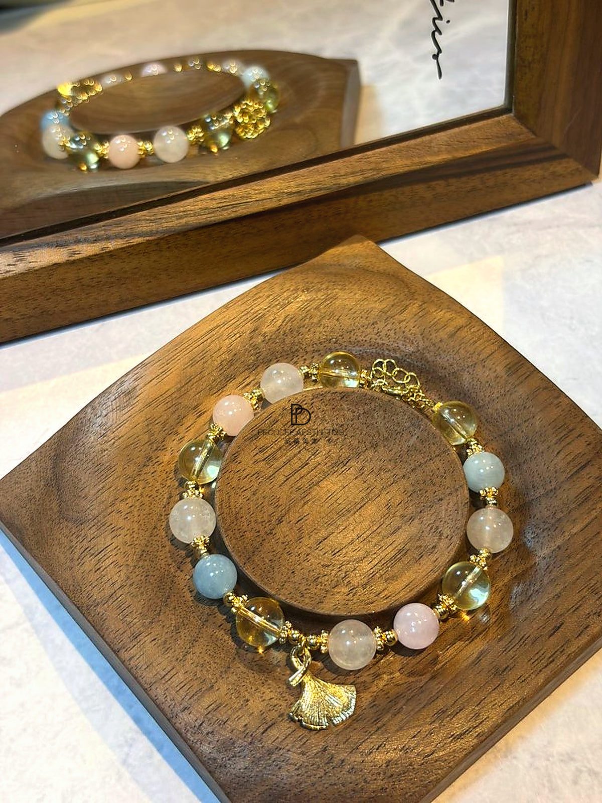Gold beaded bracelet with leaf and tassel charms, white, pale pink, and light blue beads