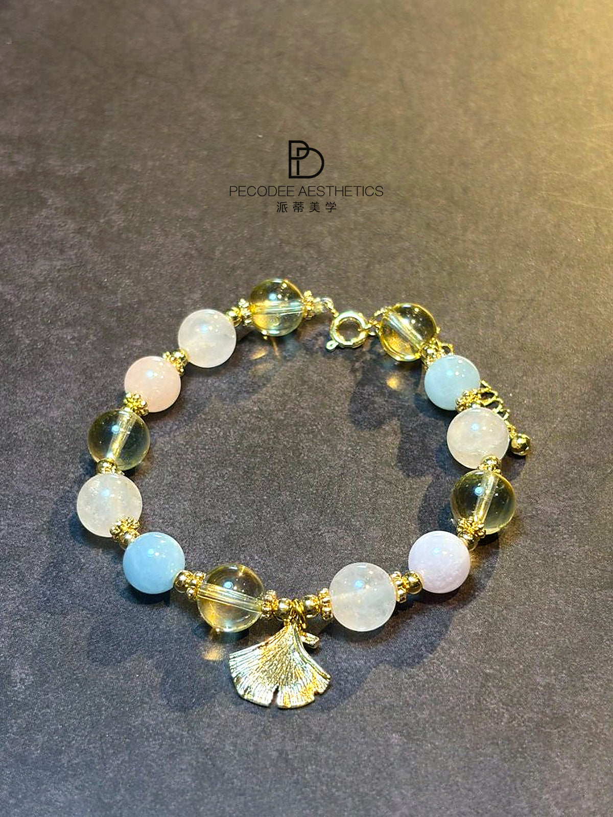 Gold beaded bracelet with white, pale pink, light blue beads and tassel charm