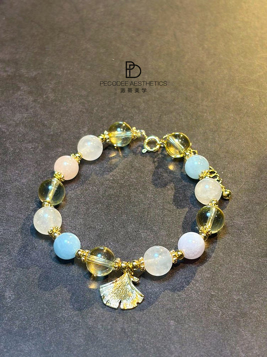 Gold beaded bracelet with white, pale pink, light blue beads and tassel charm