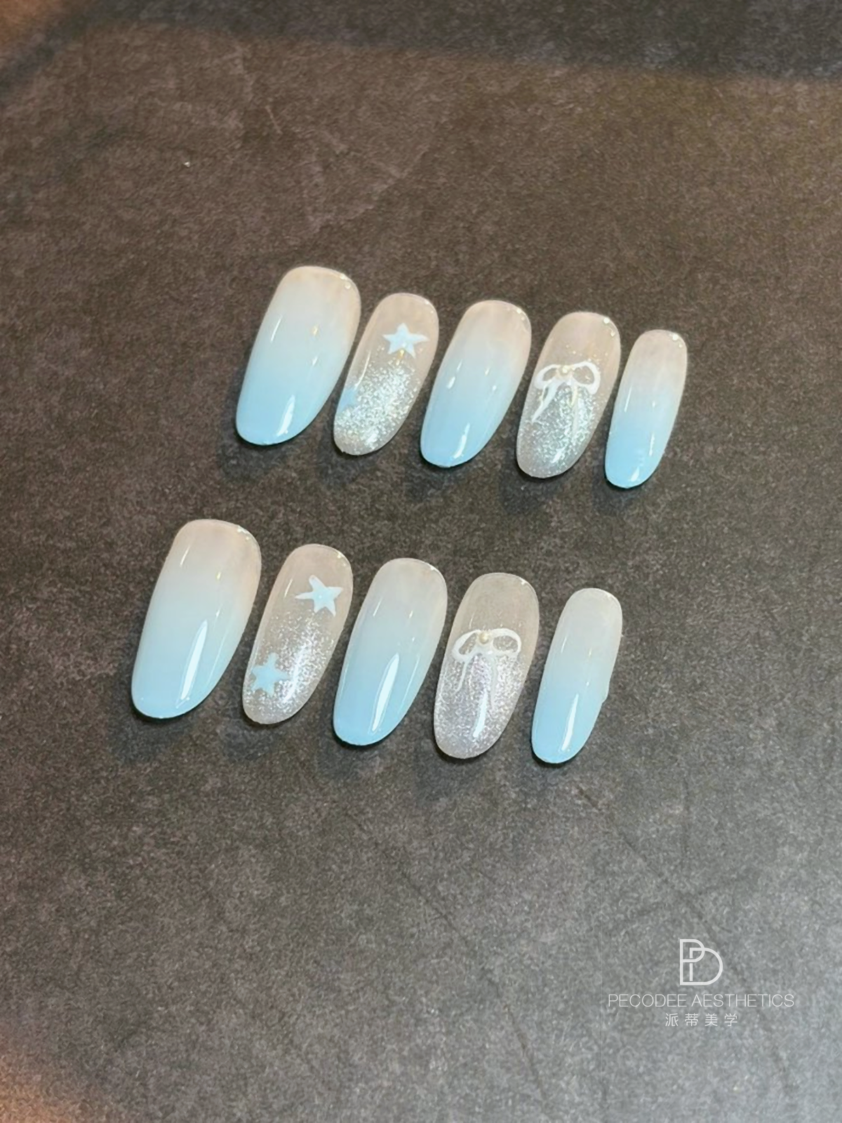 Light blue press-on nails with silver glitter accents, stars, and decorative swirls