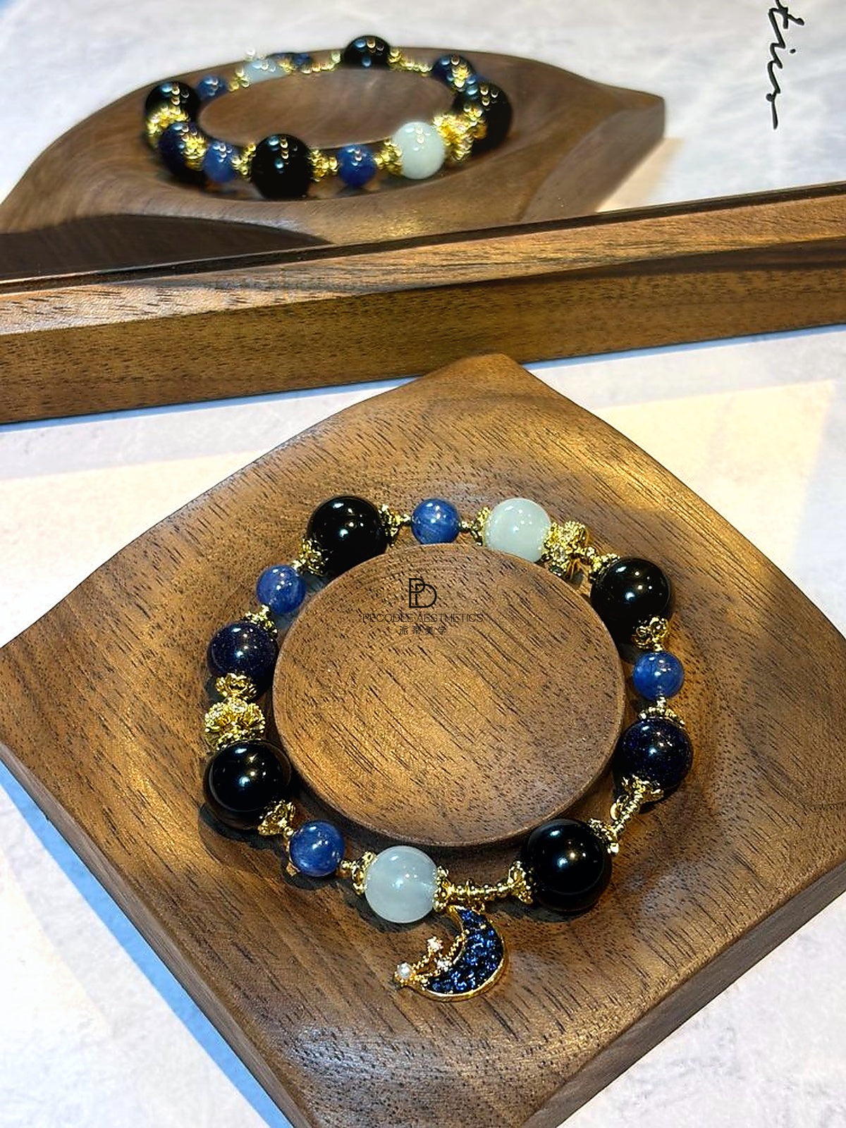 Beaded charm bracelet with pale aqua, blue, and dark beads, gold-tone crescent charm