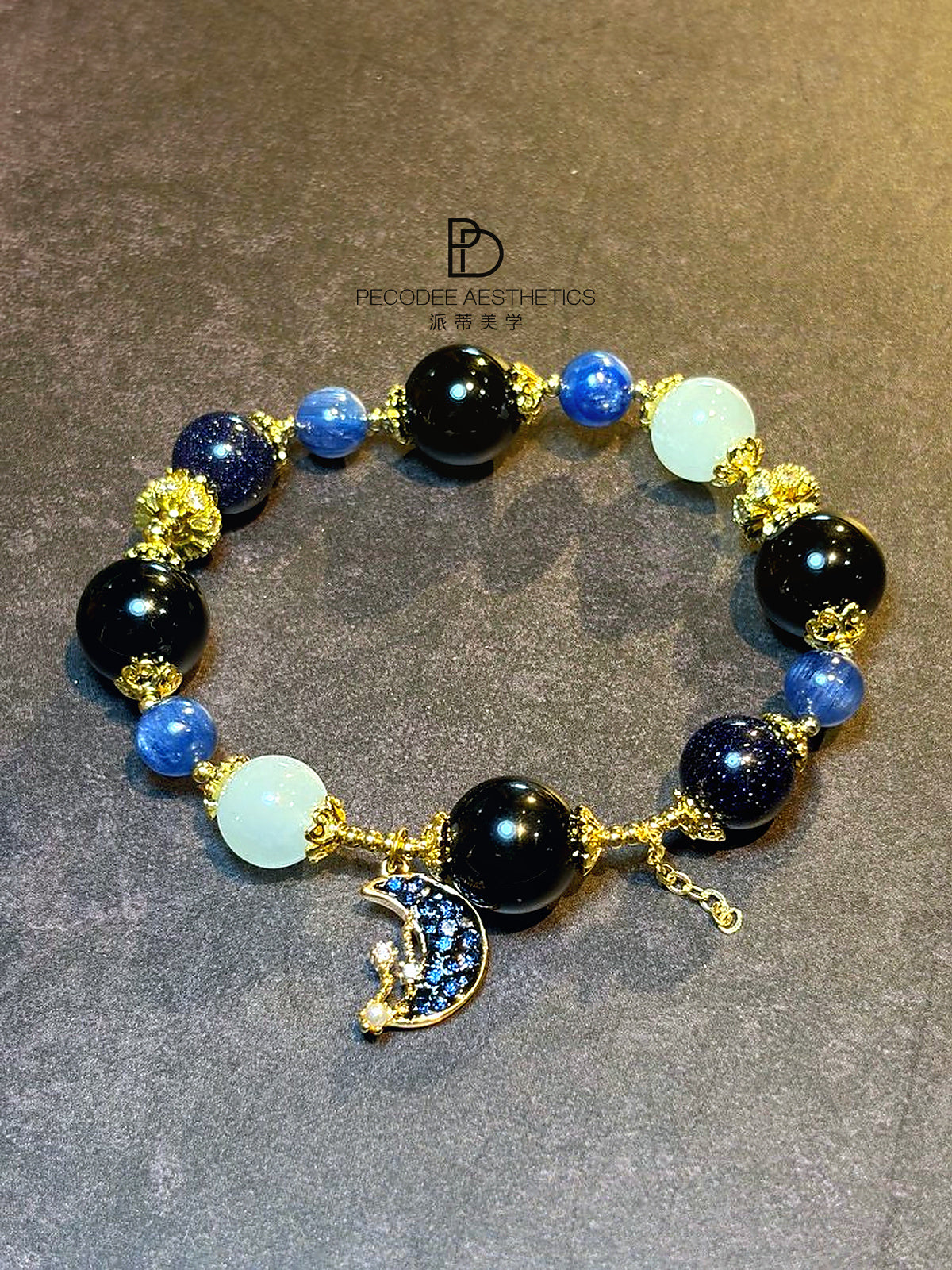 Beaded charm bracelet with blue and dark beads, pale aqua accents, gold-tone crescent charm