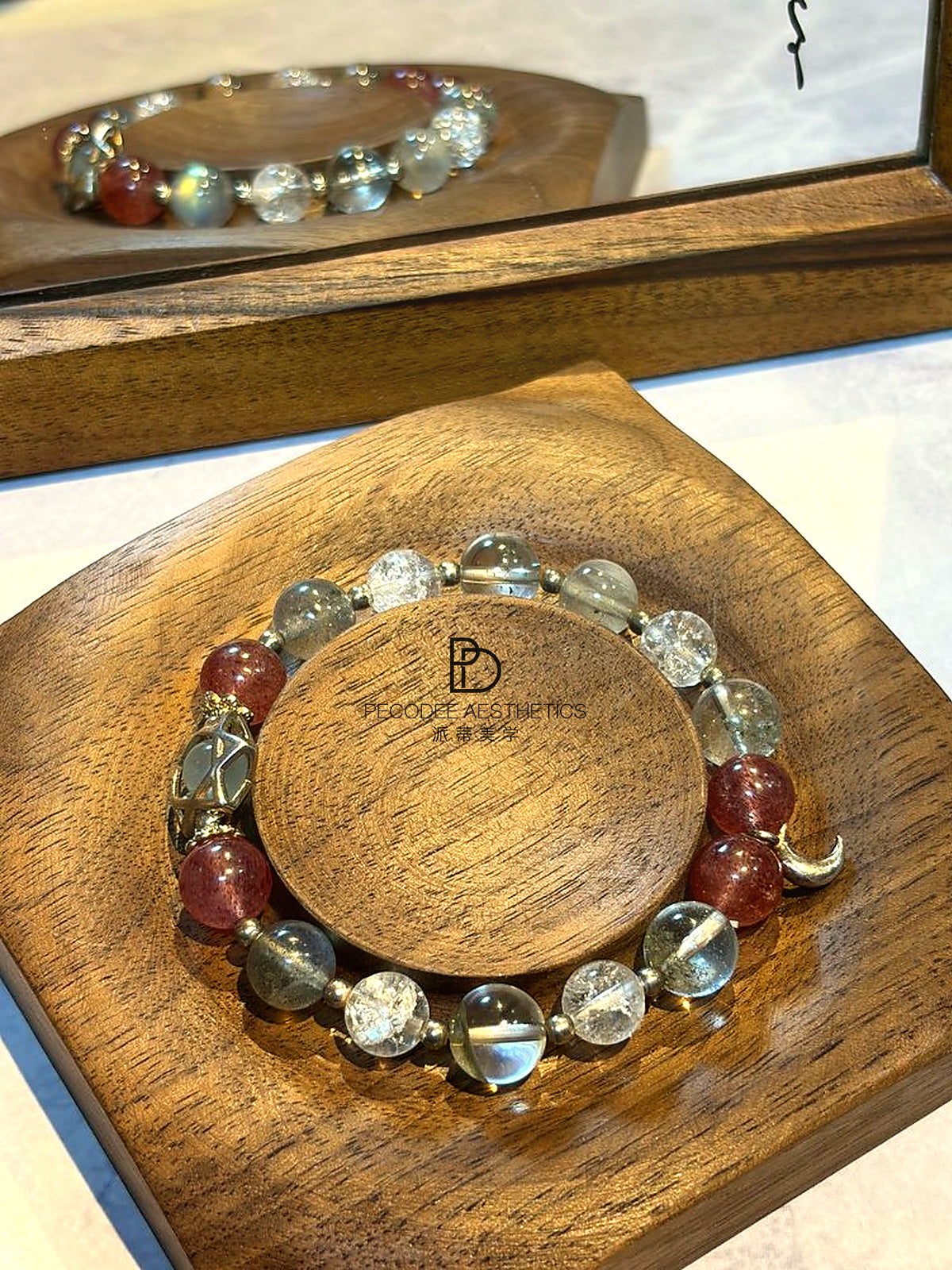 Beaded bracelet with clear, pale blue and berry-red beads, curved silver hook charm