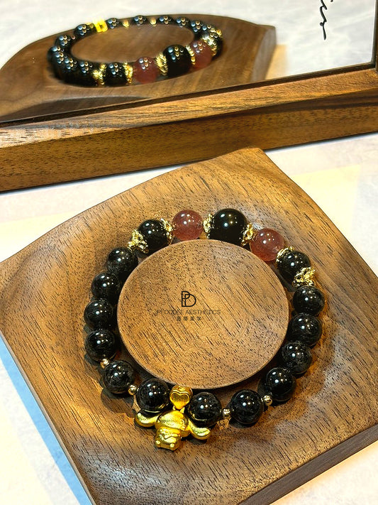 Dark beaded bracelet with gold-tone charm and brown accent beads