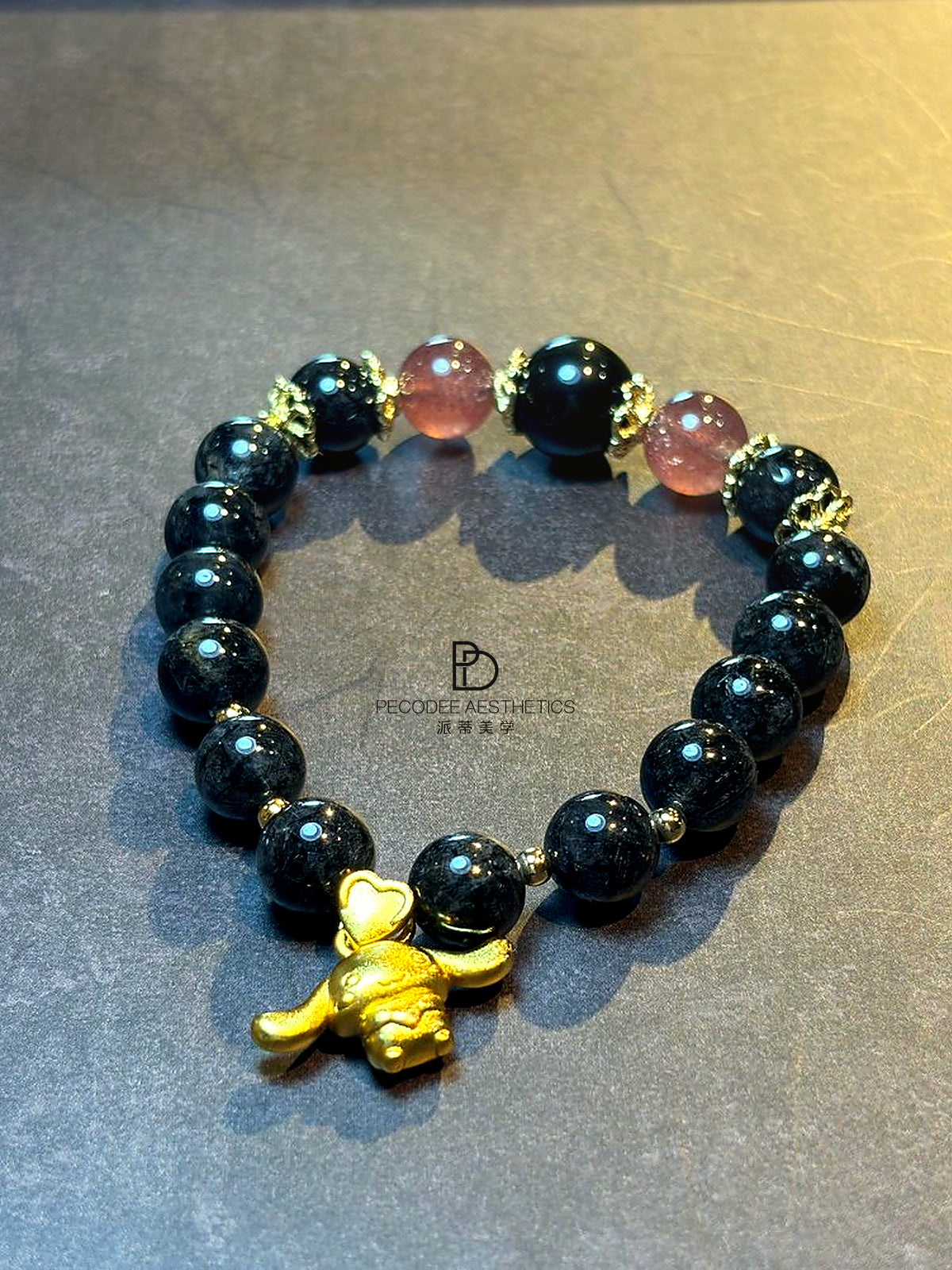Beaded bracelet with dark round beads and gold-tone charm centerpiece