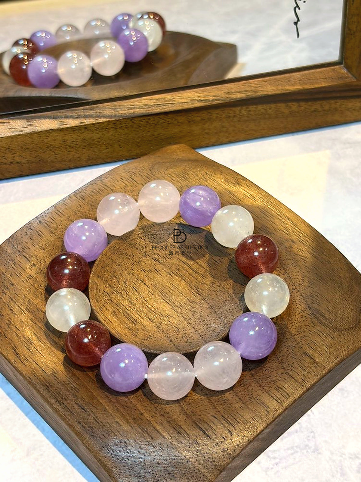 Round beaded bracelet on wooden tray with purple and white beads and two dark red beads