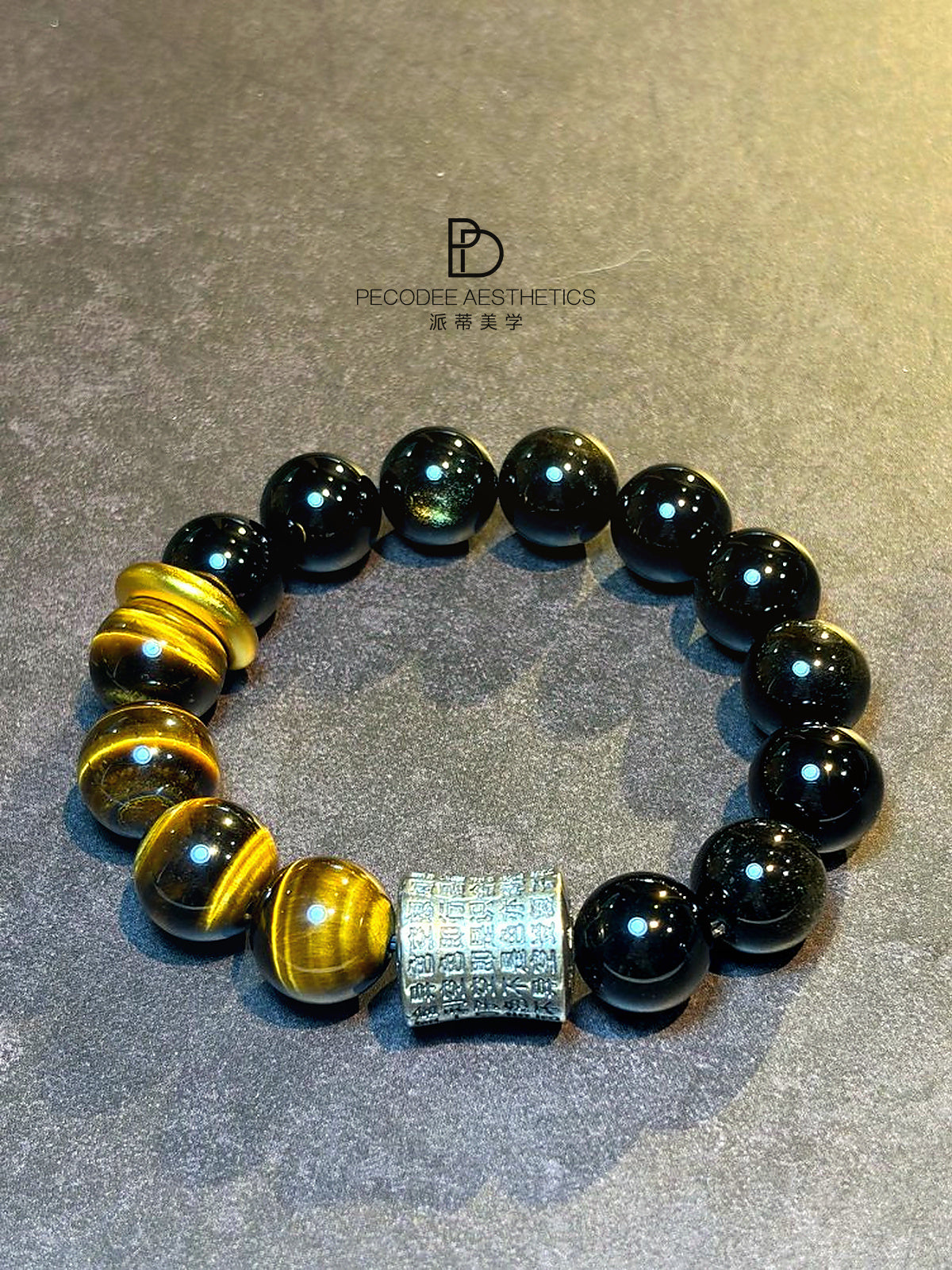 Beaded bracelet with dark round beads and gold accents, featuring a square patterned center charm.